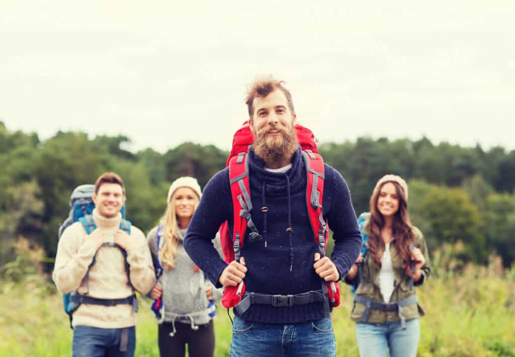 adventure, travel, tourism, hike and people concept - group of smiling friends standing with backpacks