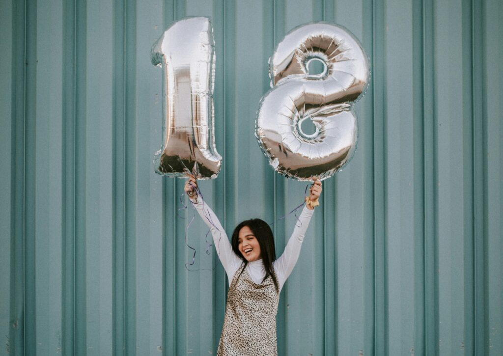 Fotobuch zum 18. Geburtstag: Eine Jugendliche hält eine 18 in der Hand